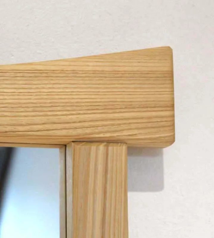 Détail de l'assemblage et du veinage du bois de frêne sur un miroir artisanal.