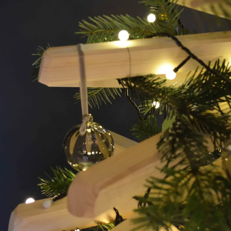 Ambiance de Noël avec guirlande lumineuse et décoration autour d’un sapin en bois