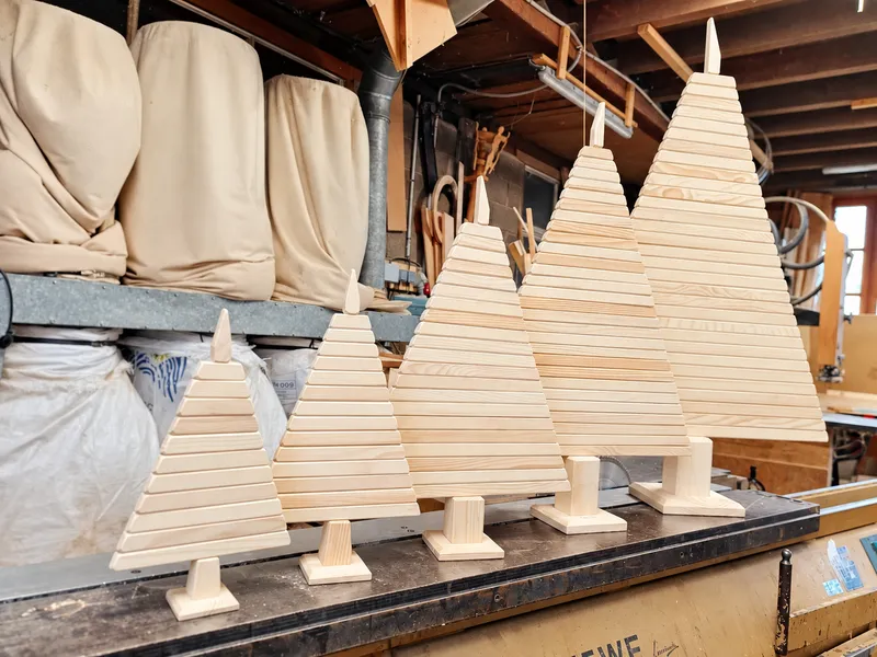 Gamme de sapins de Noël en bois artisanaux de différentes tailles dans notre atelier en Haute-Saône