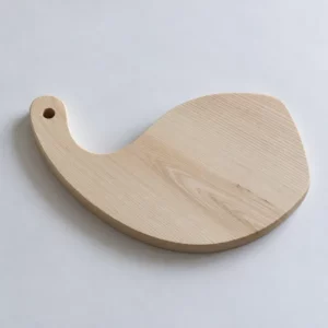 Planche à découper La Volute en frêne massif, vue générale montrant sa forme organique et son trou de suspension.